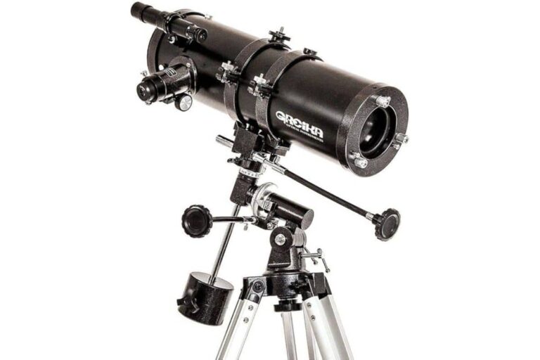 Imagem de um telescópio refletor para iniciantes, com tubo óptico preto montado em uma montagem equatorial manual fixa em um tripé prateado. O design inclui ajustes precisos, buscador auxiliar e contrapeso para estabilidade.